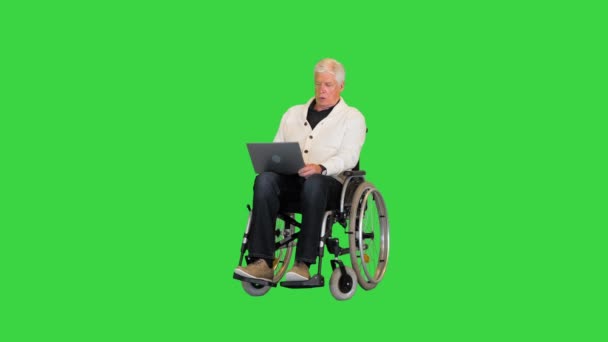 Vecchio disabile in sedia a rotelle digitando sul computer portatile su uno schermo verde, Chroma Key. — Video Stock