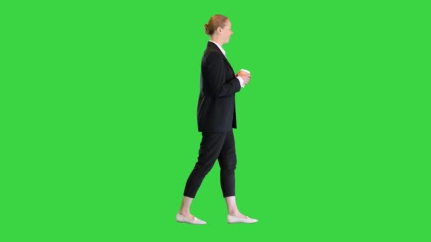 美しい若いブロンドのビジネス女性は、緑の画面上でコーヒーのカップを保持歩く,クロマキー. — ストック動画