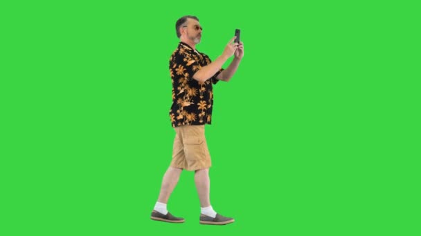 Hombre mayor turista tomando fotos por su cámara del teléfono mientras camina en una pantalla verde, Chroma Key. — Vídeos de Stock