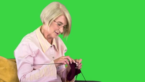 Senior πλέξιμο σε μια καρέκλα σε μια πράσινη οθόνη, Chroma Key. — Αρχείο Βίντεο