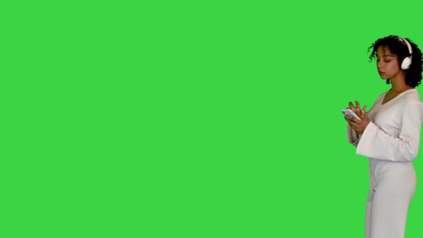 Jonge zwarte dame in het wit groovend naar muziek op een groen scherm, Chroma Key. — Stockvideo