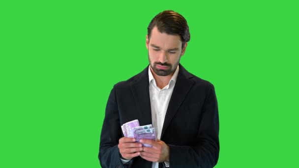 Aufgeregter Geschäftsmann steckt Euro-Scheine in seine Tasche auf einem Green Screen, Chroma Key. — Stockvideo