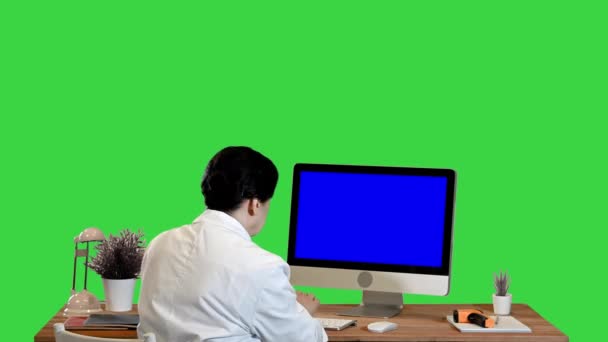 Médica idosa olha para um monitor com tela em branco Mock-up Display em uma tela verde, Chroma Key. — Vídeo de Stock