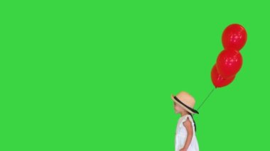 Yeşil ekranda kırmızı balonlarla yürüyen küçük kız, Chroma Key.