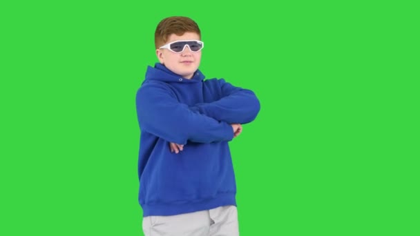 Tonåring unge bär casual kläder och solglasögon stående med armarna korsade på en grön skärm, Chroma Key. — Stockvideo