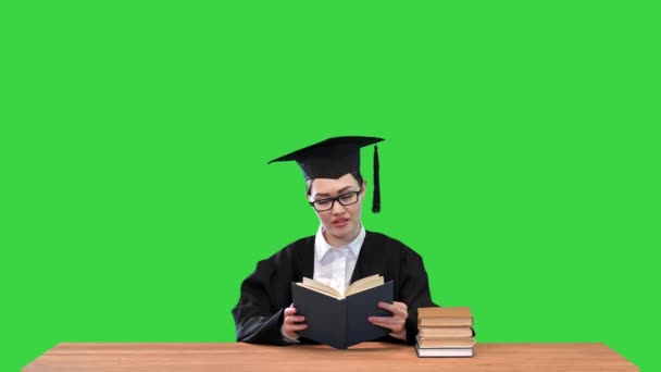 Estudiante graduada sentada en el escritorio y leyendo un libro en una pantalla verde, Chroma Key. — Vídeo de stock