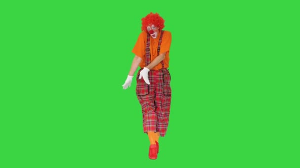 Κλόουν με κόκκινη περούκα περπατώντας και χορεύοντας με αστείο τρόπο σε μια πράσινη οθόνη, Chroma Key. — Αρχείο Βίντεο