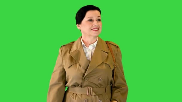 크로마 키그린 스크린에서 쇼핑백을 들고 걷고 있는 해구 코트를 입은 성숙 한 여성. — 비디오
