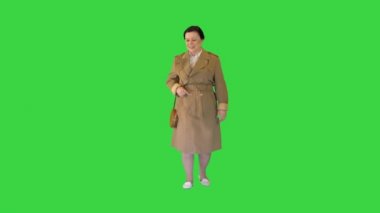 Trençkotlu şişman esmer kadın Yeşil Ekran 'da yürüyor, Chroma Key.