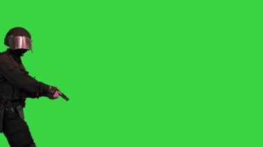 Polis SWAT silahlı bir savaşçı yeşil ekranda tabancayla yürüyor, Chroma Key.