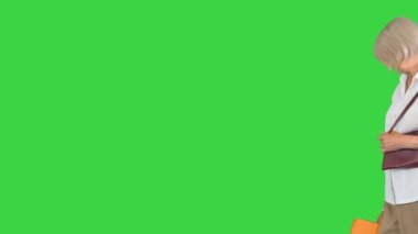 Yeşil Ekran 'da alışveriş poşetleriyle dolaşan zengin büyükanne, Chroma Key..