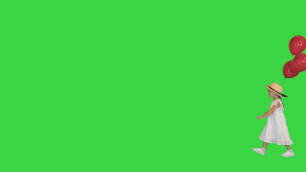 Little girl walking by with red balloons on a Green Screen, Chroma Key. — Stock Video