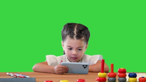 Small girl watching something on smartphone on a Green Screen, Chroma Key. — Stock Video