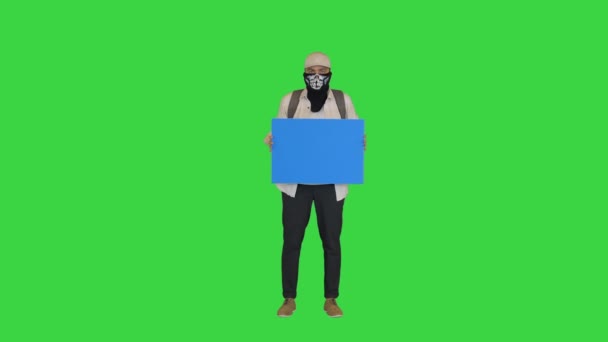 Молодий протестувальник з закритим обличчям тримає чисту дошку на зеленому екрані, Chroma Key. — стокове відео