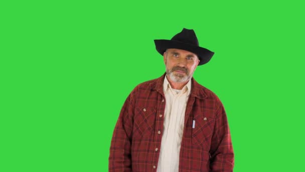 Volwassen lachende man in zwarte cowboyhoed loopt op een groen scherm, Chroma Key. — Stockvideo
