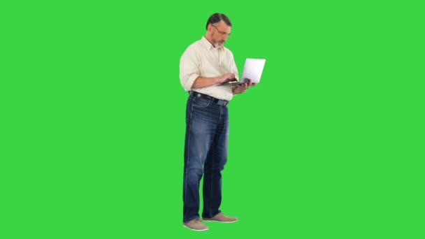Przystojny senior korzystający z laptopa i świętujący zwycięstwo na zielonym ekranie, Chroma Key. — Wideo stockowe