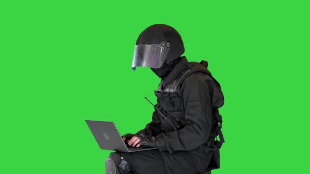 Policista nepokojů sedí a používá notebook na zelené obrazovce, Chroma Key. — Stock video