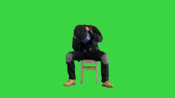 Policía antidisturbios sentado con casco apagado descansando en una pantalla verde, Chroma Key. — Vídeos de Stock