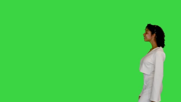 Młoda czarna dama w bieli spacery dostosowując włosy na zielonym ekranie, Chroma Key. — Wideo stockowe