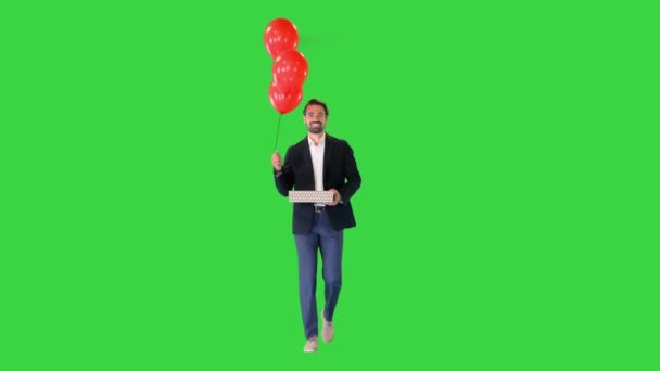 Beau mec dans un costume élégant avec un coffret cadeau et des ballons marchant sur un écran vert, Chroma Key. — Video