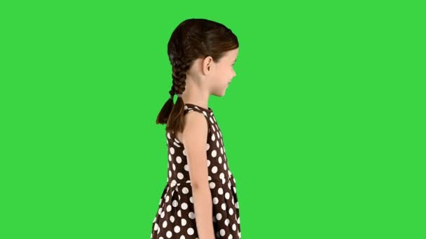 Schüchternes kleines Mädchen im gepunkteten Kleid, das mit den Händen wedelt und auf einem Green Screen spricht, Chroma Key. — Stockvideo