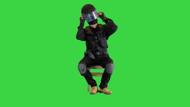 Policía antidisturbios sentado y poniéndose el casco en una pantalla verde, Chroma Key. — Vídeos de Stock