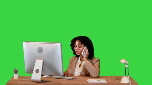 Atraktivní mladá žena mluví po telefonu sedí u počítače na zelené obrazovce, Chroma Key. — Stock video