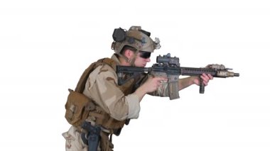 Deniz piyadesi beyaz arka planda otomatik tüfekle nişan alıyor ve ateş ediyor.