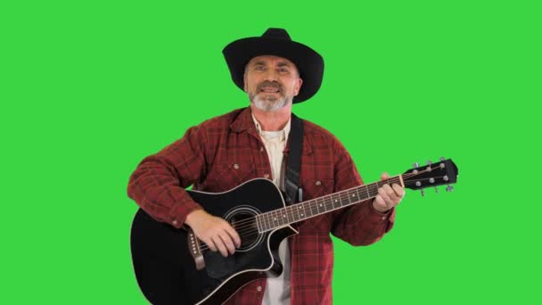 Anciano vaquero caminando, cantando y tocando la guitarra en una pantalla verde, Chroma Key. — Vídeo de stock