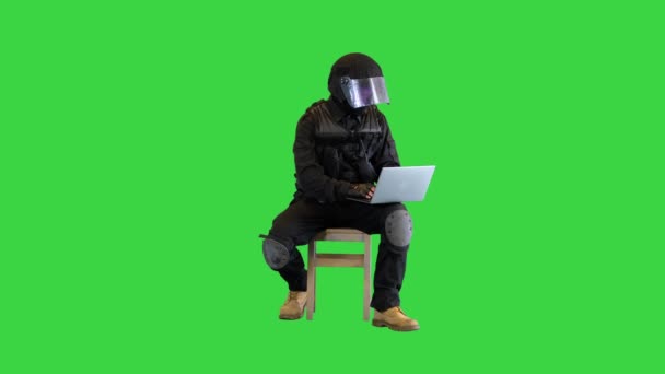 Opstandeling politieagent zitten en met behulp van laptop op een groen scherm, Chroma Key. — Stockvideo
