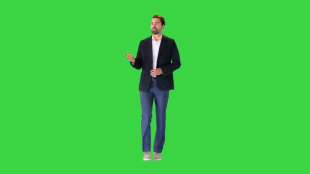 Fiatal jóképű üzletember sétál és magában beszél egy zöld vásznon, Chroma Key. — Stock videók