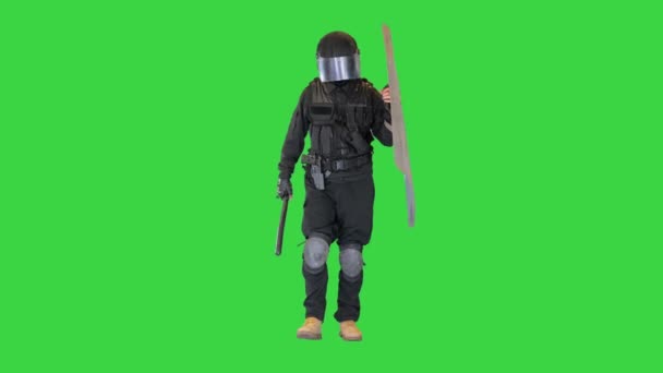 Opstandeling politieagent met een schild en stokje lopen op een groen scherm, Chroma Key. — Stockvideo