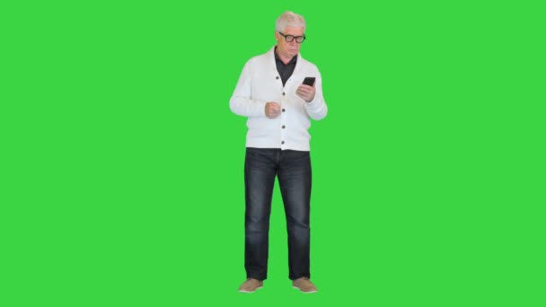 Vecchio soddisfatto utilizzando il suo smartphone su uno schermo verde, Chroma Key. — Video Stock