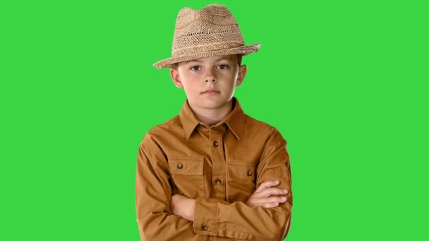 Oğlan gömlekli ve hasır şapkalı çapraz kollu poz veriyor ve sonra kollarını kalçasına koyuyor yeşil ekranda, Chroma Key. — Stok video