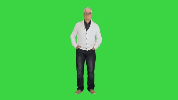 Senior man draagt een vest en kijkt naar camera doet niets op een groen scherm, Chroma Key. — Stockvideo