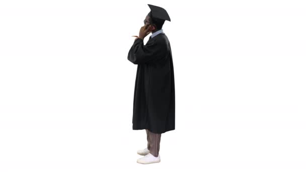 身着毕业礼服的非洲裔美国男生一边打电话一边笑，一边在白色背景下分享好消息. — 图库视频影像