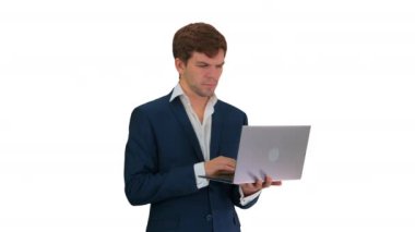 Konsantre olmuş genç işadamı beyaz arka planda dururken dizüstü bilgisayarda çalışıyor..