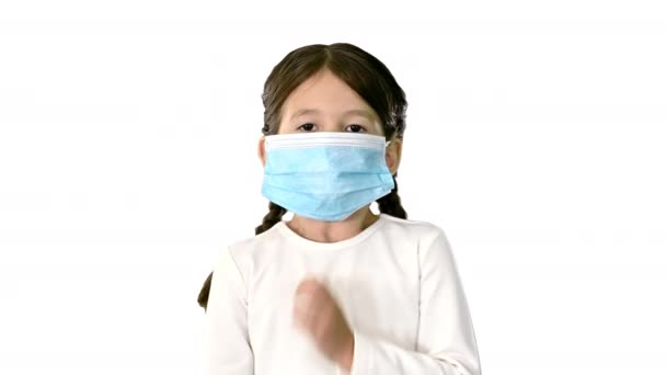 小さな女の子身に着けています保護顔マスク取りますディープ息見ますカメラオンホワイトバックグランド. — ストック動画