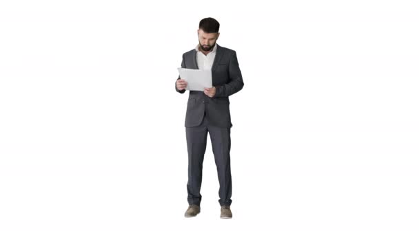 Бизнесмен стоит и читает газеты серьезно на белом фоне. — стоковое видео