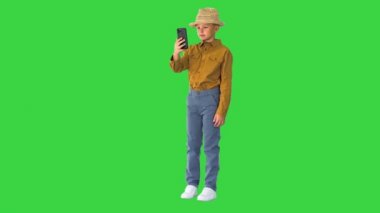Yeşil Ekran, Chroma Key 'de telefonla video görüşmesi yaparken hasır şapkalı küçük çocuk ortalıkta dolaşıyor..