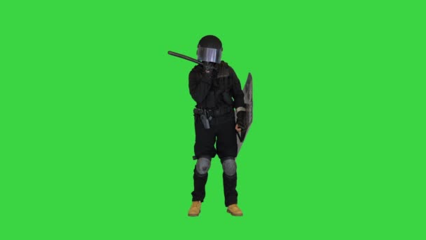 Сотрудник ОМОНа с тактической дубинкой и щитом, стоящим и трогающим его лицо на зеленом экране, хрома-ключ. — стоковое видео