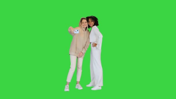 Afro-Amerikaans en een blank meisje nemen een selfie op een groen scherm, Chroma Key. — Stockvideo