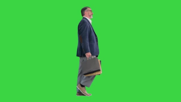 Senior zakenman loopt met boodschappentas op een groen scherm, Chroma Key. — Stockvideo