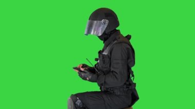 Çevik kuvvet polisi oturuyor ve yeşil ekranda akıllı telefon kullanıyor, Chroma Key.