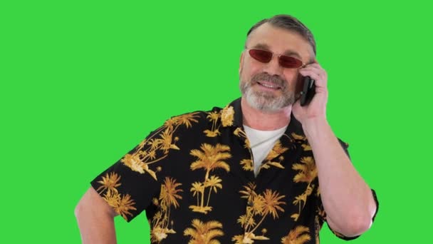 Senior man met een zonnebril praten met de smartphone op een groen scherm, Chroma Key. — Stockvideo
