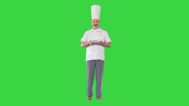 Mutlu aşçı kameraya bakıyor yeşil ekranda tatlı tutuyor, Chroma Key.