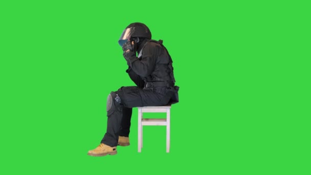 Riot policeman sitting with helmet off having rest on a Green Screen, Chroma Key. — Stock Video