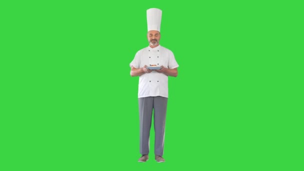 快乐的厨师看着摄像机，手里拿着绿色屏幕上的甜点，铬钥匙. — 图库视频影像