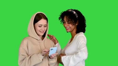 Afrikalı Amerikalı ve Kafkasyalı bir kız yeşil ekranda internette geziniyor, Chroma Key.