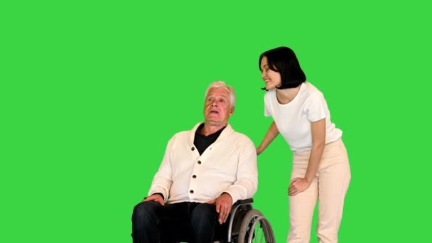 Senior man in een rolstoel praten met een jonge vrouw op een groen scherm, Chroma Key. — Stockvideo